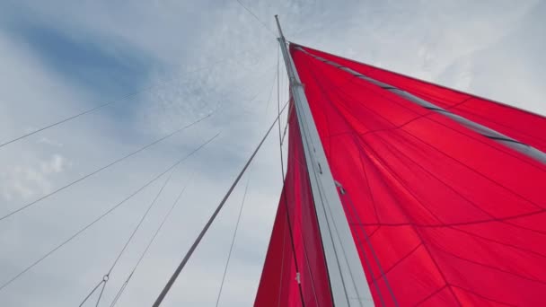 Den nedre vyn på en mast av segelbåten med ett segel av röd färg, ett klart soligt väder, den blå himlen med moln, runt video — Stockvideo