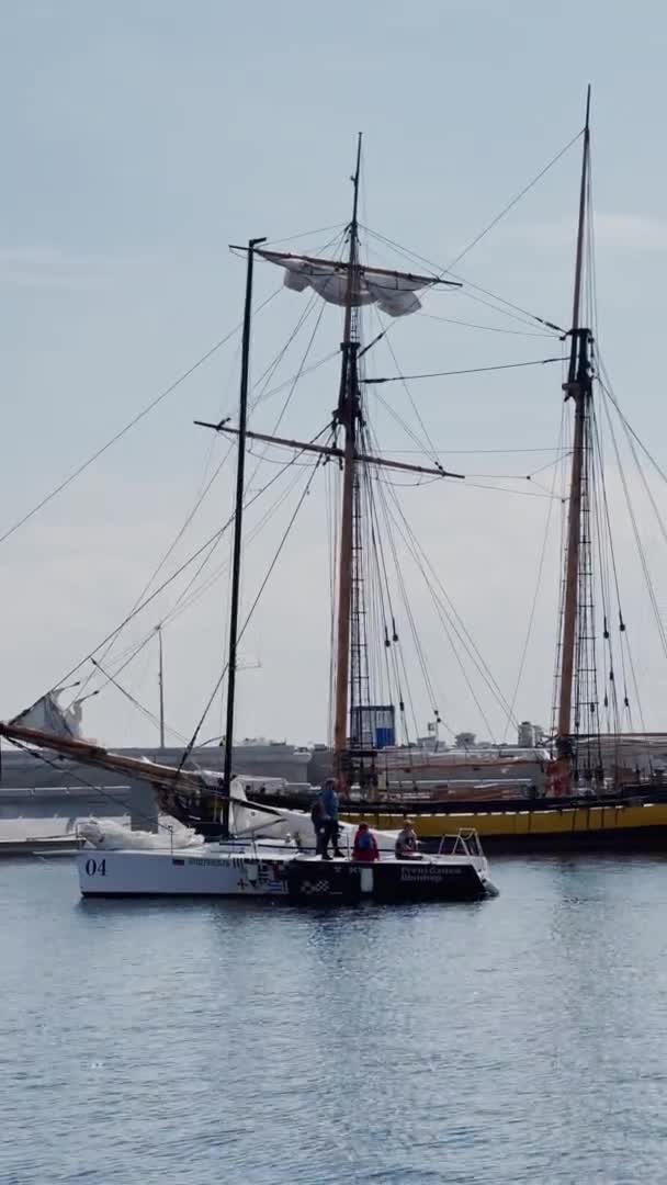 Rússia, São Petersburgo, 18 de junho de 2021: A antiga fragata de vela está estacionada no novo porto de Hércules, está perto do arranha-céu Centro de Lakhta pela Gazprom companhia petrolífera, poucos veleiros esportivos estão estacionando perto de navio velho — Vídeo de Stock