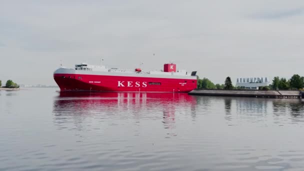 Russia, San Pietroburgo, 18 giugno 2021: L'enorme traghetto con camion si muove su un corso d'acqua lasciando la città, colore rosso, il grande indice la città di Leningrado, un grattacielo Lakhta su uno sfondo, nuvoloso — Video Stock