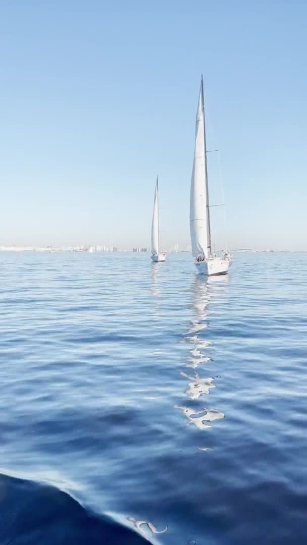 Ryssland, St Petersburg, 18 Juni 2021: Vissa segelbåtar i en lista går till sjöss, stilla vatten, den klara himlen, segel regatta, reflektion av segel på vattnet, små vågor — Stockvideo