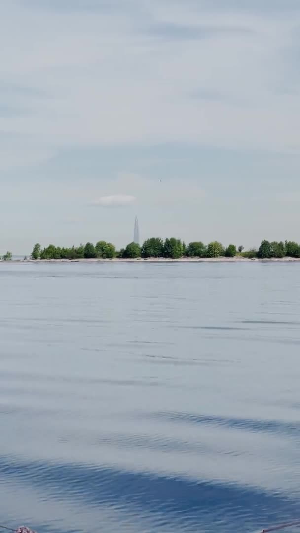 Rusko, Petrohrad, 18. června 2021: Pohled na mrakodrap Lakhta Center z vody, budova ropné společnosti Gazprom, fasádní zasklení za jasného počasí, vrchol budovy, voda v blízkosti budovy — Stock video