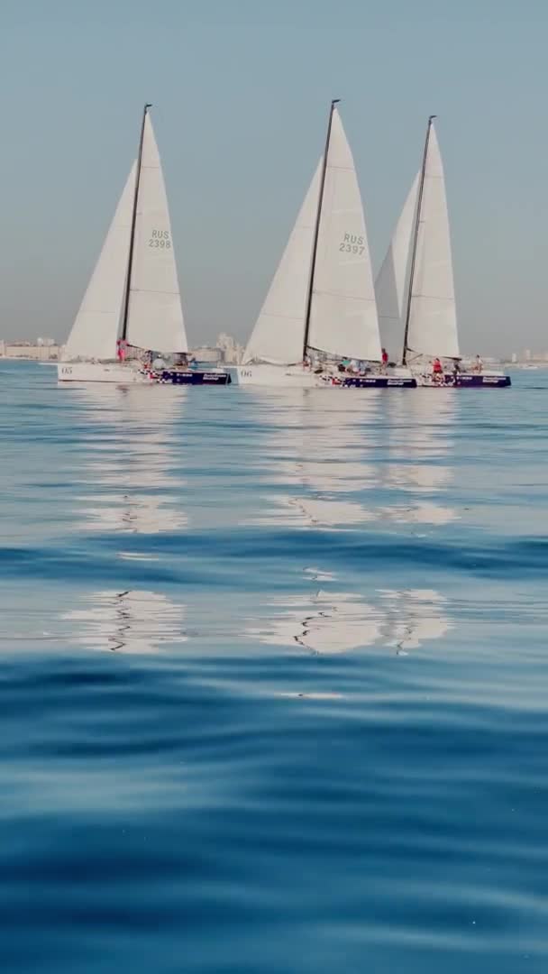 Russia, St.Petersburg, 18 June 2021: Some sailboats slowly go on water, still water, the clear sky, sail regatta, reflection of sail on the water, small waves, blue water — Stock Video