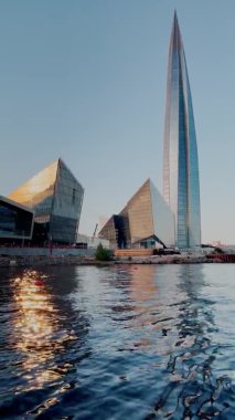 Rusya, St. Petersburg, 18 Haziran 2021: Gökdelen Lakhta Center 'a gün batımında sudan bakış, petrol şirketi Gazprom' un binası, açık havada parlayan bir cephe, bina zirvesi