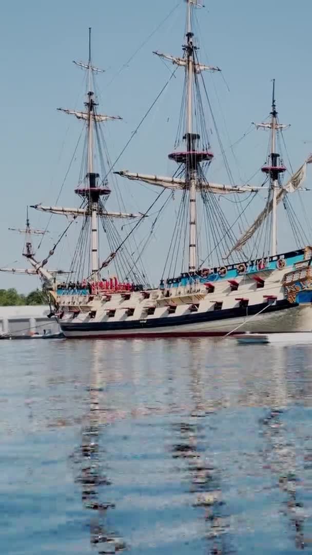 Vertikale Aufnahmen der antiken Fregatte, die an sonnigen Tagen im Hafen geparkt wird, magische Spiegelungen auf dem Wasser, klares Wetter, Blick vom Wasser aus — Stockvideo