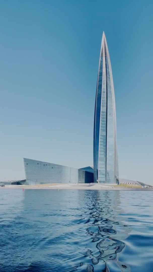 Russia, St. Petersburg, 18 June 2021: View on skyscraper Lakhta Center from water, building of the oil company Gazprom, a facade glazing at clear weather, building peak, water near a building — Stock Video
