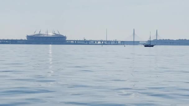 Russland, St. Petersburg, 20. Juni 2021: Neues Stadion Gazprom Arena und Schrägseilbrücke am Horizont, ruhiges Wasser im Finnischen Meerbusen, klarer Himmel, Reflexion der Sonne — Stockvideo