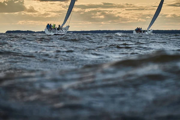 Competition of two sailboats on the horizon in sea at sunset, the amazing storm sky of different colors, race, big waves, sail regatta, cloudy weather, only main sail, sun beams — Stock Photo, Image