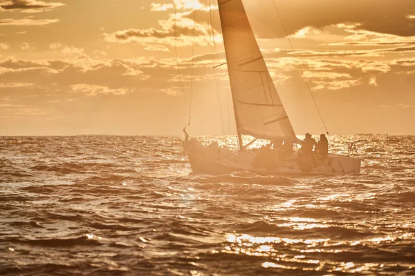 夕日の海の地平線に孤独な帆船、さまざまな色の嵐の空、大きな波、帆レガッタ、曇りの天気、唯一のメイン帆、太陽の光ビーム — ストック写真