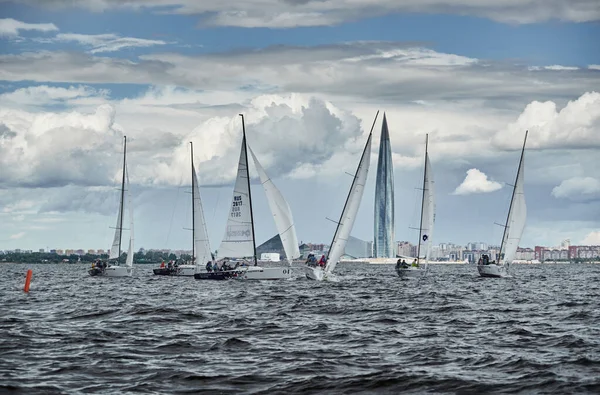 Russia, St. Petersburg, 23 July 2021: Competition of few sailboats in regatta at storm weather, skyscraper Lakhta center by Gazprom oil company on background, race, big waves, team work — Stock Photo, Image