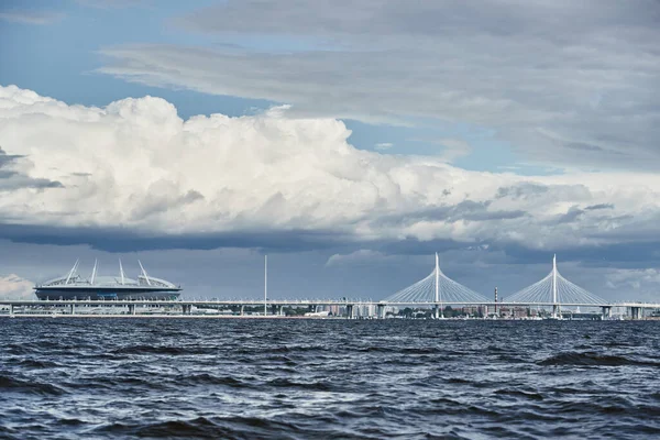 Россия, Санкт-Петербург, 20 июня 2021 года: Новый стадион "Газпром Арена" и кабельный мост на горизонте, Финский залив, облачное небо, бурная погода, большие облака — стоковое фото