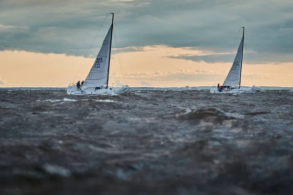 Russland, St. Petersburg, 23. Juli 2021: Wettbewerb zweier Segelboote am Horizont im Meer bei Sonnenuntergang, der erstaunliche Gewitterhimmel in verschiedenen Farben, Rennen, große Wellen, Segelregatta, bewölktes Wetter, Sonnenstrahlen — Stockfoto