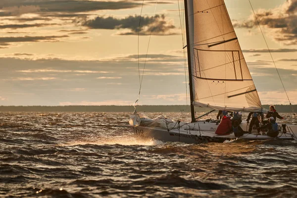Russia, St. Petersburg, 23 July 2021: Competition of sailboats on the horizon in sea at sunset, the amazing storm sky of different colors, race, big waves, sail regatta, sun beams, team work — Stock Photo, Image