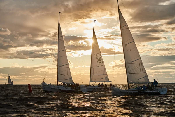 Russia, St.Petersburg, 23 July 2021: Competition of Three sailboats on the horizon in sea at sunset, the amazing storm sky of different colors, race, big waves, sail regatta, cloudy weather, sun beams — Stock Photo, Image