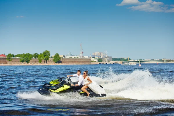 02.06.2013, Russia, Saint-Petersburg: Newlyweds go on jet skis, the bride and groom on the background of Peter and Paul Fortress, the water area of the Neva river, boat, beach, blue sky, sunny weather — Stock Photo, Image