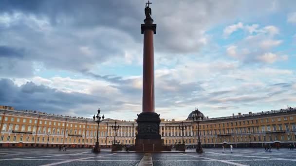 Россия, Санкт-Петербург, 02.08.2015: Дворцовая площадь и Александровская колонна, движение камеры снизу вверх, закат, розовые облака, много людей на площади, мокрые булыжники — стоковое видео