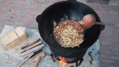 Ateşte büyük bir dökme demir kazanda Özbek milli çanak pilav, altın kahverengi, kuzu, havuç, koyun yağı, yağ kuyruk, susam yağı, sarımsak kadar doğranmış soğan kızartma