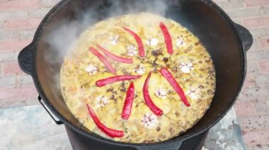 Özbek milli yemek pilavı nın içinde büyük bir dökme demir kazanda, dilimlenmiş kırmızı havuç, soğuk su, sarımsak ve kırmızı biber bütün eklemek, kaynamaya başlar, pirinç, kuzu, koyun yağı, yağ kuyruk