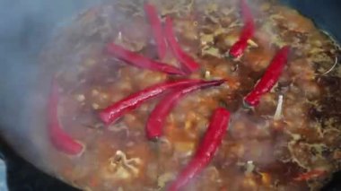 Özbek milli yemek pilav ateşte büyük bir dökme demir kazan, dilimlenmiş kırmızı havuç, soğuk su, sarımsak ve kırmızı biber, kaynama, pirinç, kuzu, koyun yağı, yağ kuyruk, susam yağı bütün ekleyin