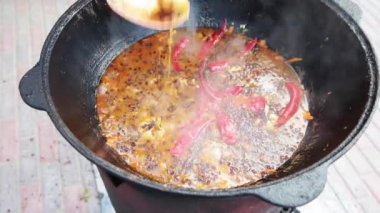 Özbek milli yemek pilavı nın içinde büyük bir dökme demir kazanda, dilimlenmiş kırmızı havuç, böğürtlen, sarımsak ve kırmızı biber, kaynar, pirinç, kuzu, koyun yağı, yağ kuyruğu, susam yağı