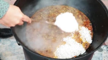 Özbek milli yemek pilavı nın üzerine büyük bir dökme demir kazanı, dilimlenmiş kırmızı havuç, böğürtlen, sarımsak ve kırmızı biber, pirinç, kuzu, koyun yağı, yağ kuyruğu, susam yağı eklenir