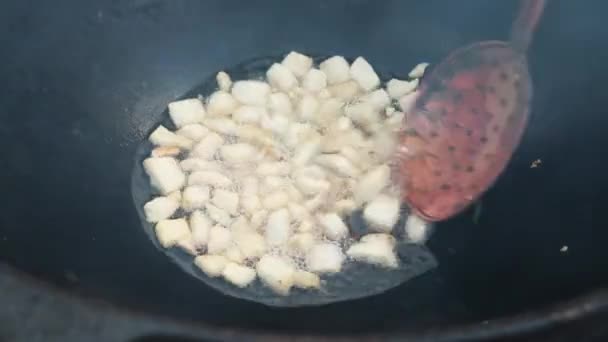 Uzbecký národní pokrm pilaf ve velkém litinovém kotli na ohni, proces vaření, smažené kousky tuku ocas, základ tvoří jídlo rýže, jehněčí, mrkev, skopový tuk, sezamový olej, cibule, česnek, kmín semena, pepř, zirvak, fergana — Stock video