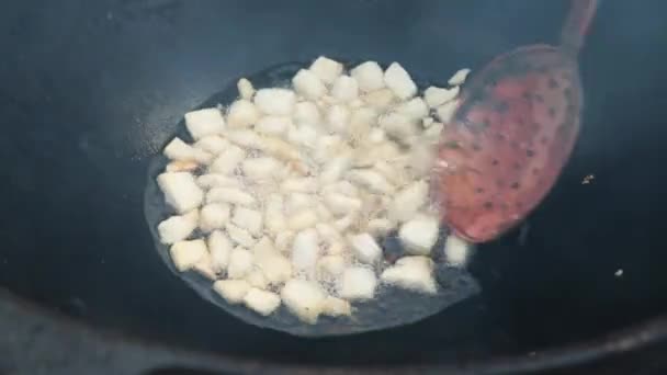 Usbekisches Nationalgericht Pilaf in einem großen gusseisernen Kessel auf dem Feuer, der Kochprozess, gebratene Fettschwanzstücke, Grundlage für Lebensmittel Reis, Lamm, Karotten, Hammelfett, Sesamöl, Zwiebeln, Knoblauch, Kreuzkümmel, Pfeffer, Zirvak, Fergana — Stockvideo