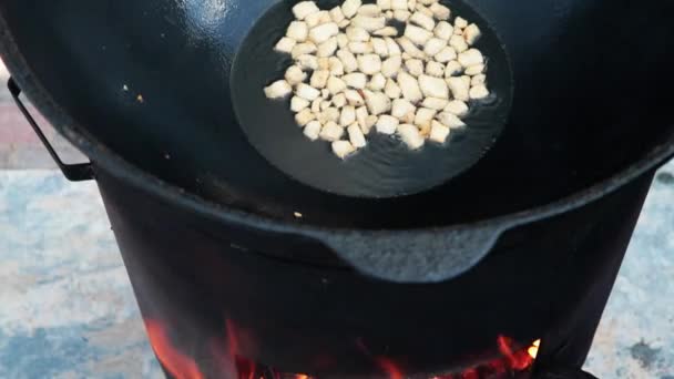 Uzbecki narodowy pilaf naczyniowy w dużym żeliwnym kotle na ognisku, proces gotowania, smażone kawałki tłustego ogona, podstawa stanowiąca ryż spożywczy, jagnięcina, marchew, tłuszcz baraniny, olej sezamowy, cebula, czosnek, nasiona kminku, pieprz, cyrak, fergana — Wideo stockowe