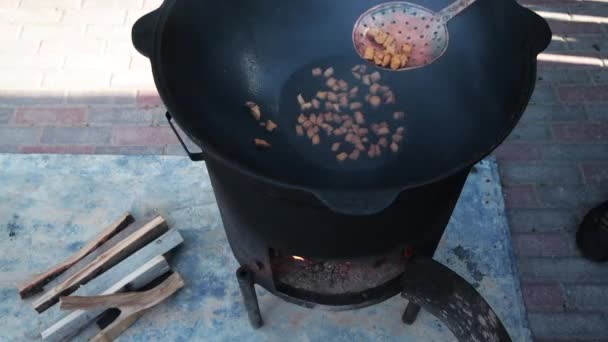 Pilaf plato nacional uzbeko en un gran caldero de hierro fundido en el fuego, el proceso de cocción, trozos fritos de cola de grasa, base que constituye arroz para alimentos, cordero, zanahoria, grasa de cordero, aceite de sésamo, cebolla, ajo, semillas de comino, pimienta, zirvak, fergana — Vídeo de stock