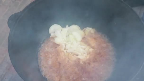 乌兹别克国菜皮拉夫在一个大铸铁锅火上，炒洋葱，直到金棕色，羊肉，胡萝卜，羊肉脂肪，脂肪尾巴，芝麻油，大蒜 — 图库视频影像