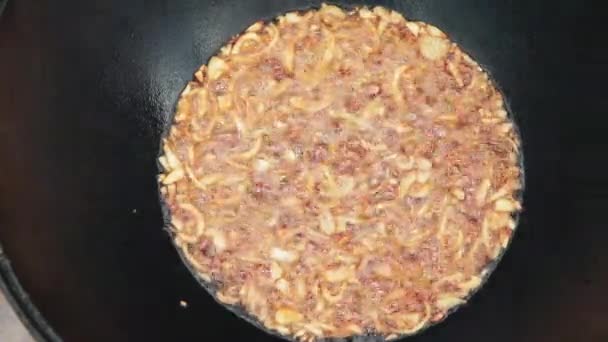 Oezbeekse nationale gerecht Pilaf in een grote gietijzeren ketel op het vuur, bak de gehakte ui tot goud bruin, lam, wortel, schapenvlees, de dikke staart, sesamolie, knoflook — Stockvideo