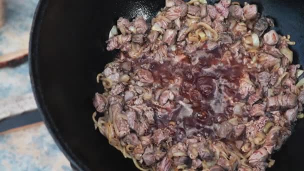 Plat national ouzbek pilaf dans un grand chaudron en fonte sur le feu, ajouter les morceaux d'agneau et faire frire, riz, carotte, graisse de mouton, la queue grasse, huile de sésame, oignon, ail, piment rouge — Video