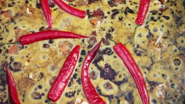 Usbekisches Nationalgericht pilaf in einem großen gusseisernen Kessel auf dem Feuer, in Scheiben geschnittene rote Karotten, kaltes Wasser, fügen Sie ganzen Knoblauch und rote Chilischote, kochend, Reis, Lamm, Hammelfett, den fetten Schwanz, Sesamöl — Stockvideo