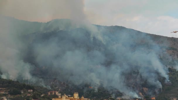 Frankrike, Menton, 09.09.2015: branden på sluttningarna av bergen på gränsen mellan Frankrike och Italien, Menton och Ventimiglia, brinnande hus och skogen, en massa rök, eld släcka flygplan — Stockvideo