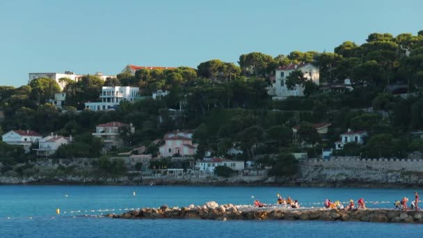 Frankrike, Menton, 2015.08.27: stranden Menton, Roquebrune Cap Martin, Provence Alpes Côte dazur, azurblå vatten, bad många barn på plast ponton, jakter på bakgrund, segelbåt — Stockvideo