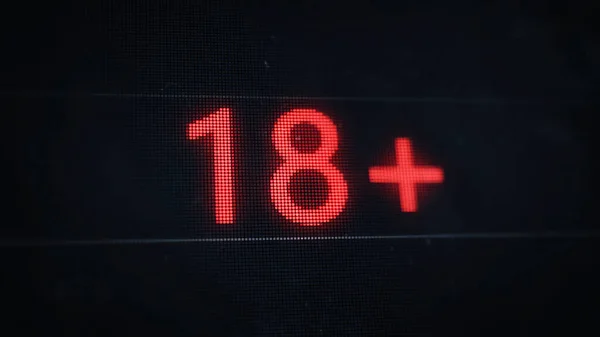 Under 18 rating sign. 18+ red pixel text on old dusty screen.