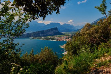 Nago-Torbole yakınlarındaki Busatte-Tempesta patikasından Garda Gölü 'ne panoramik manzara, Torbole kasabası, yaz aylarında dağlarla çevrili, İtalya