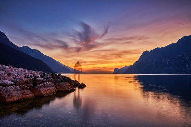 Güzel Garda Gölü 'nün dağlarla çevrili görüntüsü, Garda Gölü' nde gün batımının manzarası, güzel günbatımı renkleri, İtalya, uzun pozlardan dolayı yumuşak odak