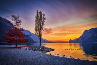 Güzel Garda Gölü 'nün dağlarla çevrili görüntüsü, Garda Gölü' nde gün batımının manzarası, güzel günbatımı renkleri, İtalya, uzun pozlardan dolayı yumuşak odak
