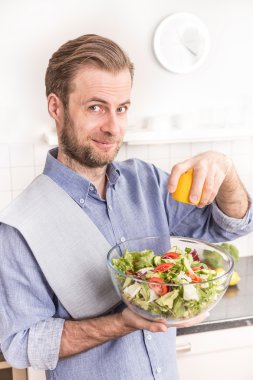 Mutlu gülümseyen adam mutfakta taze sebze salatası yapmak