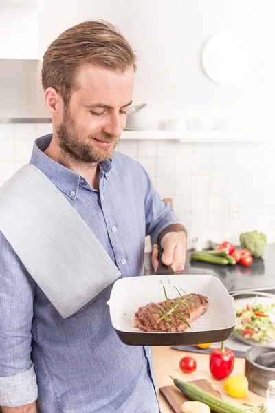 Glücklicher Mann oder Koch mit Pfanne und gegrilltem Steak mit Rosmarin — Stockfoto