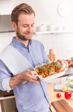 Adam ya da Şef holding çiğ tavuk sopaları ile çanak kavurma