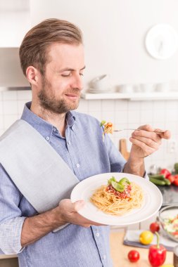 Mutlu gülümseyen adam yeme spagetti bolognese mutfakta