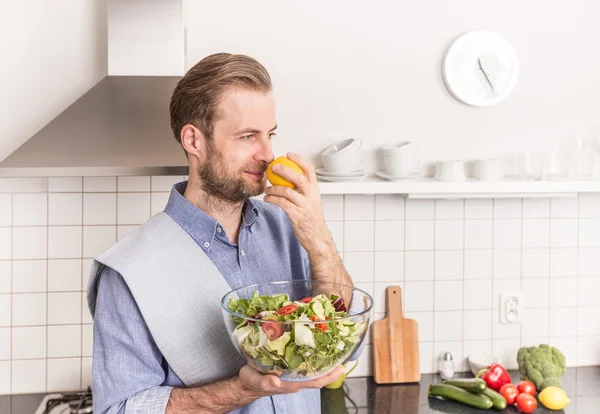 Glücklich lächelnder Mann mit frischem Gemüsesalat in der Küche — Stockfoto