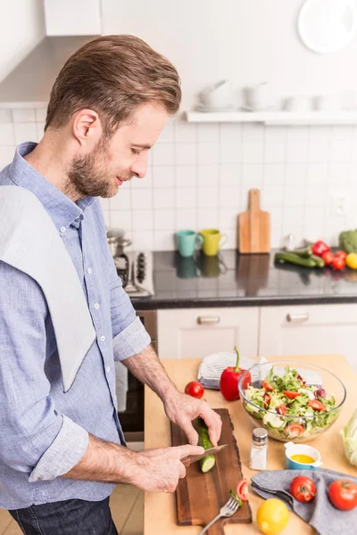 Glücklich lächelnder Mann, der Gemüse hackt, um Salat zu machen — Stockfoto