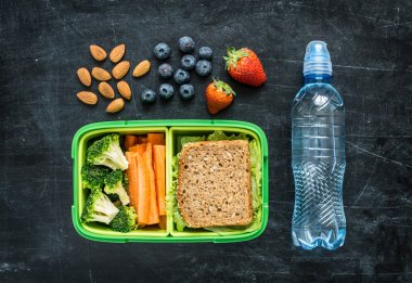 School lunch box with sandwich, vegetables, water and fruits clipart