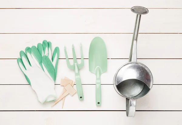 Primavera - herramientas de jardinería, regadera y guantes en madera blanca — Foto de Stock