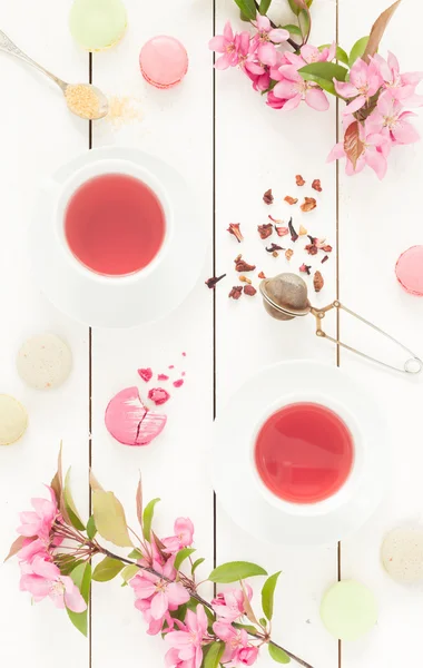 Różowy herbaty owocowe i pastelowych francuskie macarons ciasta na biały — Zdjęcie stockowe