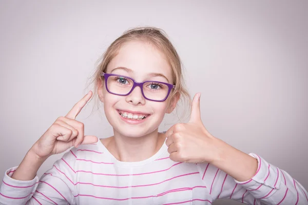 Menina criança loira feliz em óculos mostrando polegares para cima gesto . — Fotografia de Stock