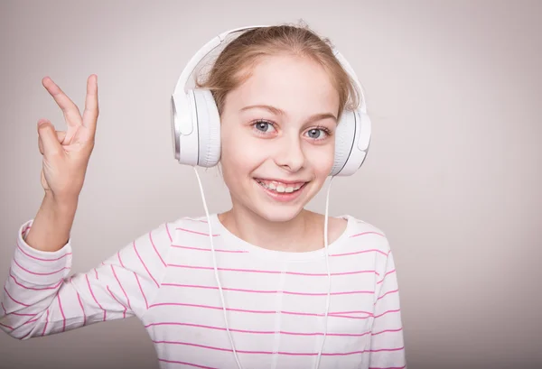 Felice sorridente bambina ascoltando musica in cuffie bianche . — Foto Stock