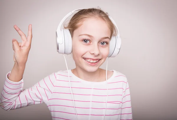 Menina sorridente feliz ouvindo música em fones de ouvido brancos . — Fotografia de Stock